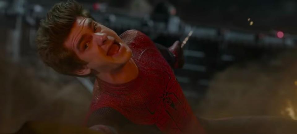 Peter hanging from a bridge while holding a burning car in "The Amazing Spider-Man"