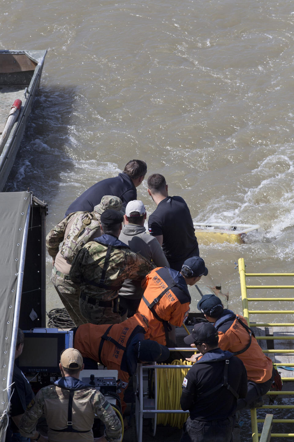 Members of the rescue crew pull out an underwater robotic probe from the waters of the Danube river as search operations continue where a sightseeing boat had capsized in Budapest, Hungary, Saturday, June 1, 2019. Hungarian authorities predicted it would take an extended search to find the 21 people still missing after a boat carrying South Korean tourists was rammed Wednesday night by a cruise ship and sank.(AP Photo/Marko Drobnjakovic)