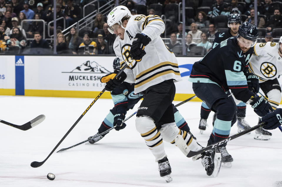 Boston Bruins forward David Pastrnak, left, skates against Seattle Kraken defenseman Adam Larsson, right, during the first period of an NHL hockey game, Monday, Feb. 26, 2024, in Seattle. (AP Photo/Stephen Brashear)