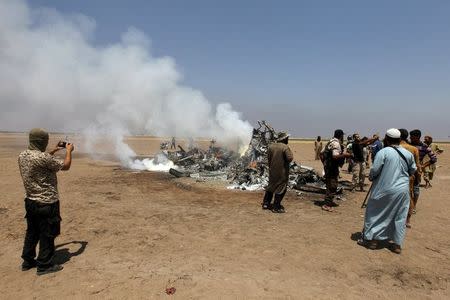 Rebel fighters and civilians inspect the wreckage of a Russian helicopter that had been shot down in the north of Syria's rebel-held Idlib province, Syria August 1, 2016. REUTERS/Ammar Abdullah