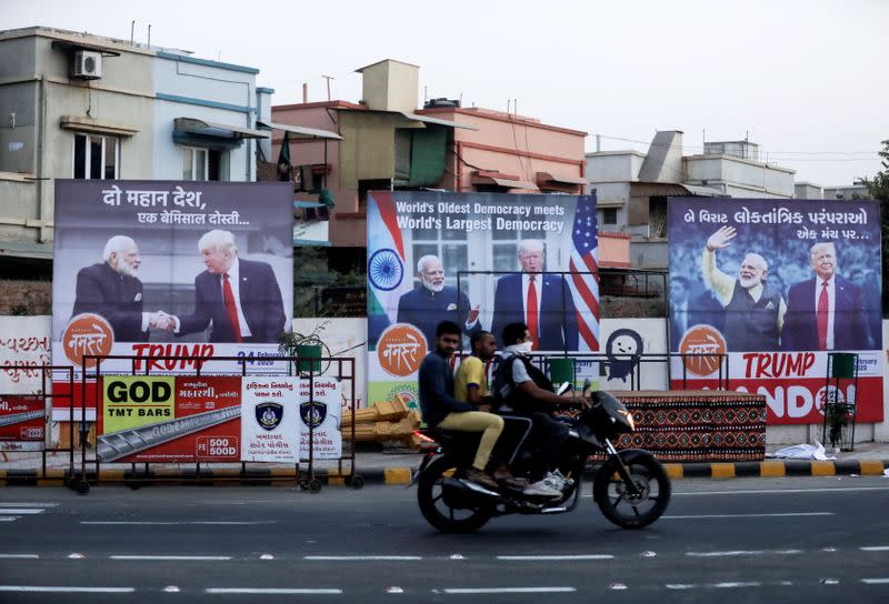 Men ride a motorcycle past hoardings of Indian Prime Minister Narendra Modi and U.S. President Donald Trump in Ahmedabad