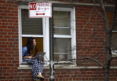 A woman sits in her window as she watches police outside the apartment of movie actor Philip Seymour Hoffman after he was found dead in New York February 2, 2014. REUTERS/Joshua Lott