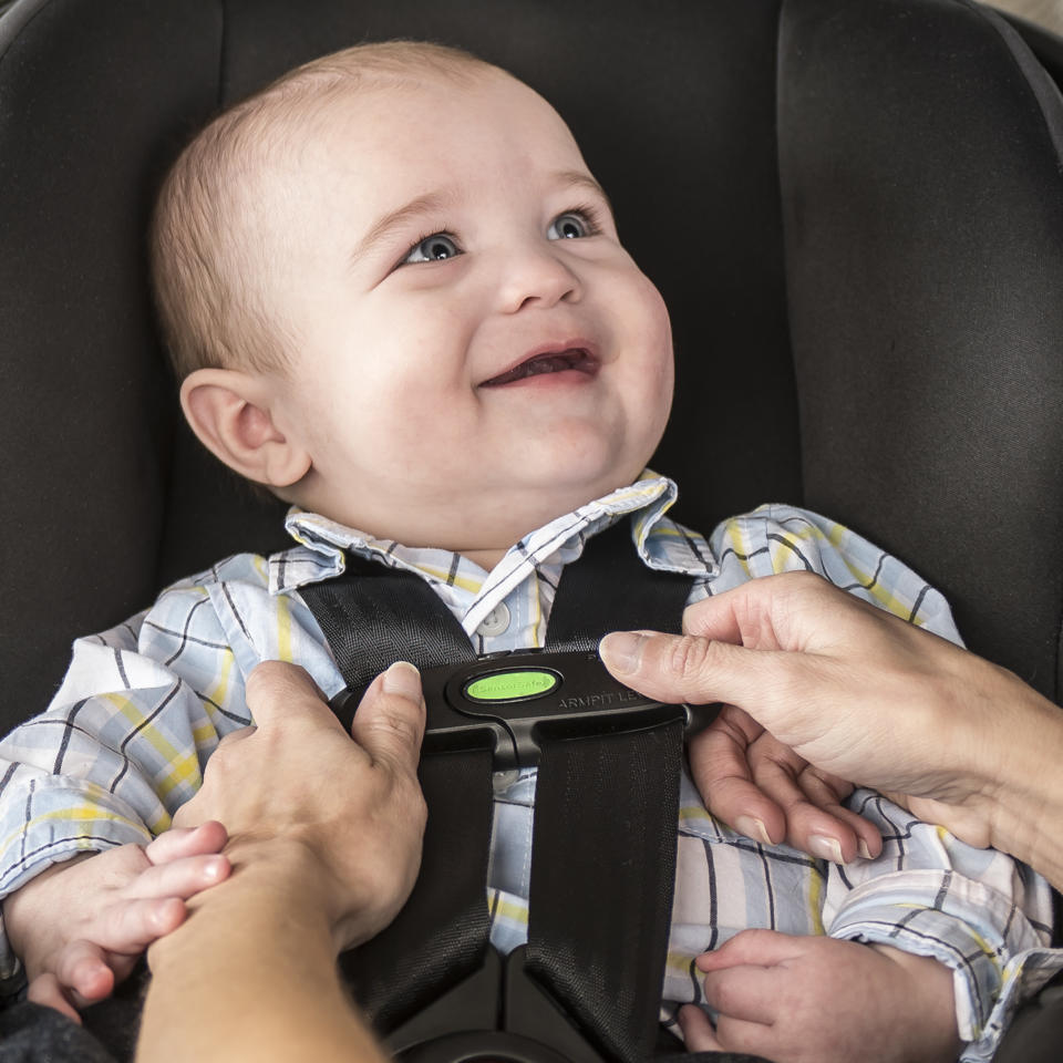 A baby is snapped into a car seat.