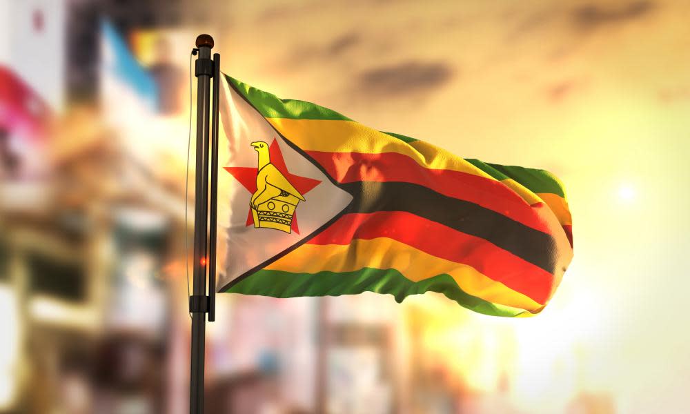 Zimbabwe Flag Against City Blurred Background At Sunrise Backlight