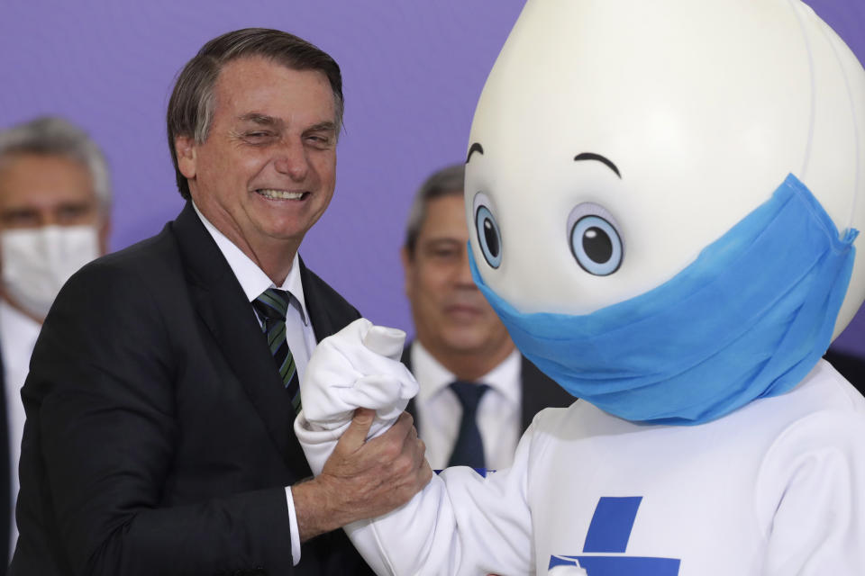 Brazilan President Jair Bolsonaro poses for photos with the mascot of his nation's vaccination campaign, named "Ze Gotinha," or Joseph Droplet, during a ceremony to present the National Vaccination Plan Against COVID-19 at Planalto presidential palace in Brasilia, Brazil, Wednesday, Dec. 16, 2020. (AP Photo/Eraldo Peres)