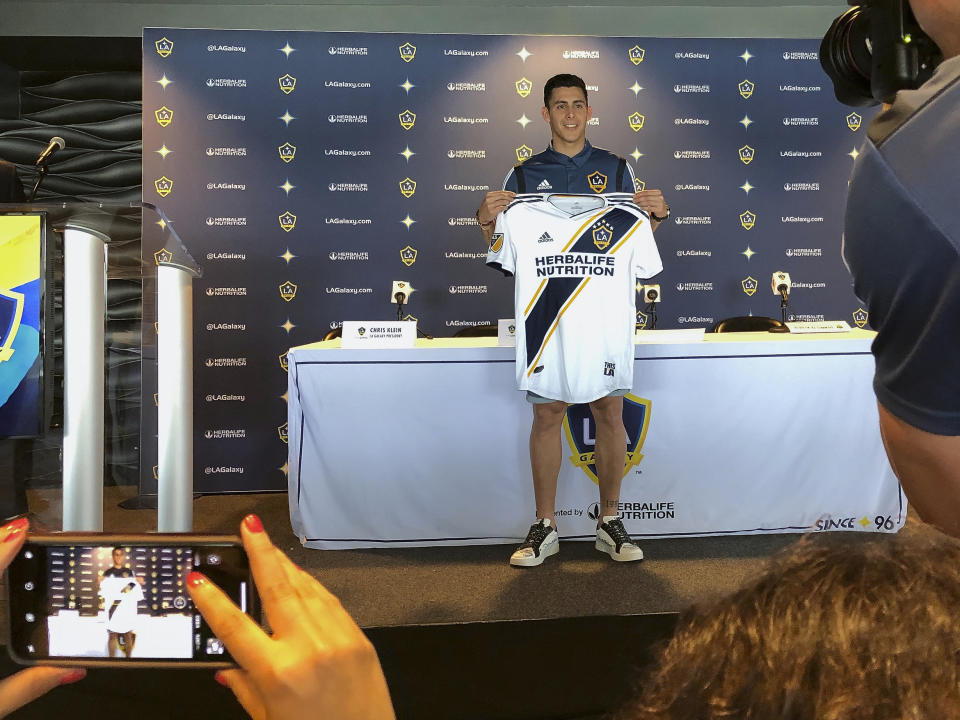 Forward Cristian Pavón of Argentina, holds up his new LA Galaxy jersey as he is introduced to the media at Dignity Health Sports Park in Carson, Calif., Thursday, Aug. 8, 2019. The LA Galaxy acquired Pavón on loan from Argentina's Boca Juniors this week in one of the biggest player acquisitions in recent Major League Soccer history. (AP Photo/Greg Beacham)