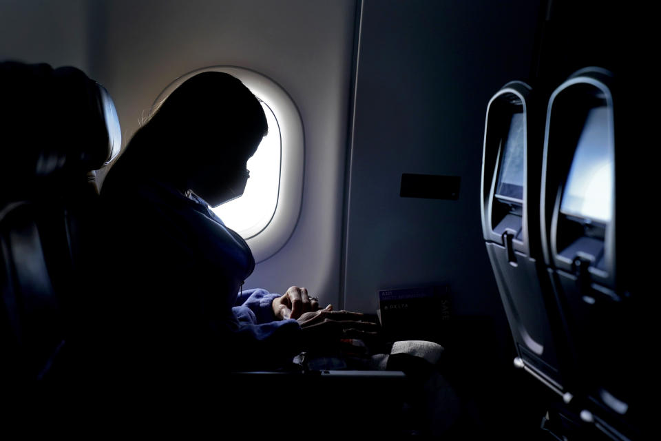 FILE - In this Wednesday, Feb. 3, 2021 file photo, a passenger wears a face mask during an airline flight after taking off from Atlanta. On Friday, April 2, 20201, the Centers for Disease Control and Prevention updated its guidance to say fully vaccinated people can travel within the U.S. without getting tested for the coronavirus or going into quarantine afterward. (AP Photo/Charlie Riedel)