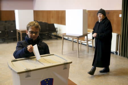 A boy casts his father's ballot at a polling station during referendum on whether to give same-sex couples the right to marry and to adopt children, in Sora, Slovenia December 20, 2015. REUTERS/Srdjan Zivulovic