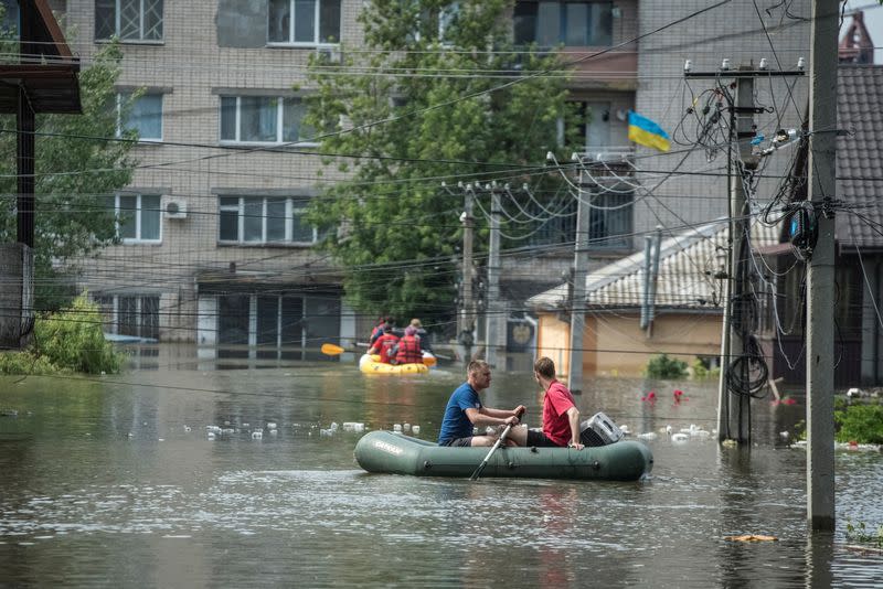 Residentes locales navegan en botes en una calle inundada durante una evacuación de una zona inundada tras la rotura de la presa de Nova Kajovka, en medio del ataque de Rusia a Ucrania, en Jersón, Ucrania
