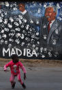 Una niña juega delante de un mural que muestra una pintura de Madiba, como es conocido Nelson Mandela en Sudáfrica.