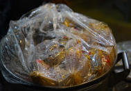 A pot full of tamales is covered with plastic as vendors wait for customers at a street stand in Mexico City, Thursday, Jan. 26, 2023. A single offering of the dish is called a tamal in Spanish. It comes from the Nahuatl word "tamalli," which means wrapped. (AP Photo/Fernando Llano)