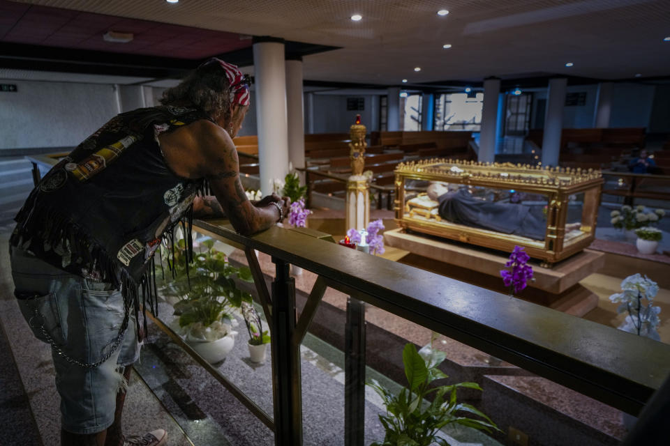 A man pauses in front of the relics of Francesco Possenti, known as St. Gabriele in the cript of the St. Gabriele dell'Addolorata sanctuary in Isola del Gran Sasso near Teramo in central Italy Sunday, June 18, 2023, as he participates in an annual bikers pilgrimage. (AP Photo/Domenico Stinellis)