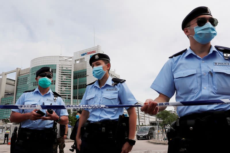 Police officers stand guard outside the headquarters of Apple Daily and Next Media after media mogul Jimmy Lai Chee-ying, founder of Apple Daily was detained by the national security unit in Hong Kong