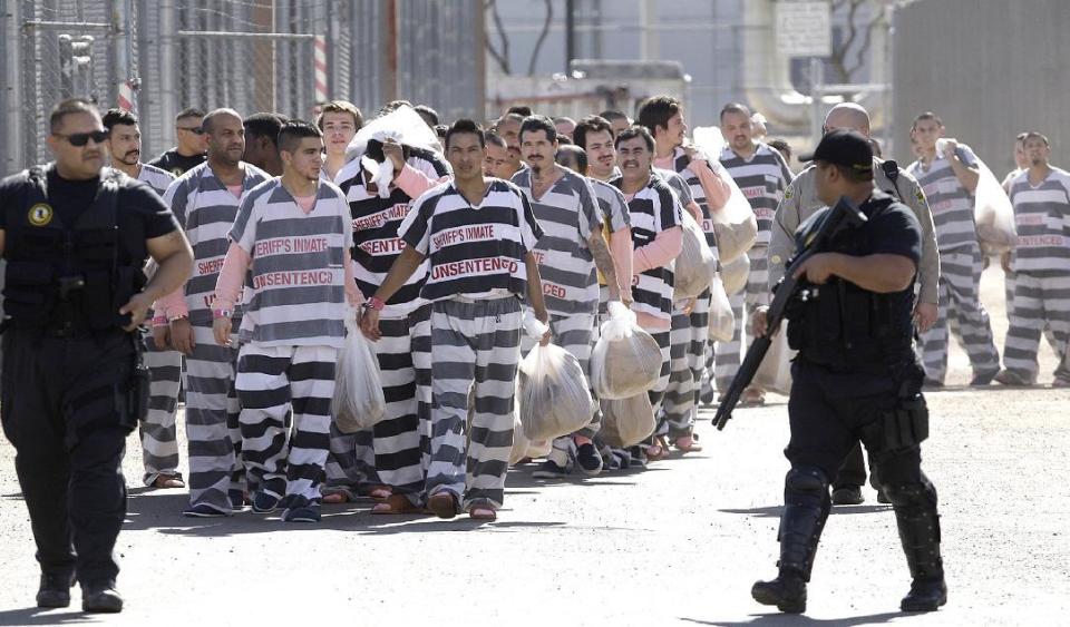 FILE - In this Feb. 4, 2009, file photo, approximately 200 convicted illegal immigrants are handcuffed together and moved into a separate area of Tent City, by order of Maricopa County Sheriff Joe Arpaio, for incarceration until their sentences are served and they are deported to their home countries, in Phoenix. Paul Penzone who defeated Arpaio in the November election announced Friday, Feb. 17, 2017 that he is ending a policy that keeps immigrants locked up in his jails past their release date to give federal authorities extra time to launch deportation proceedings. (AP Photo/Ross D. Franklin, File)