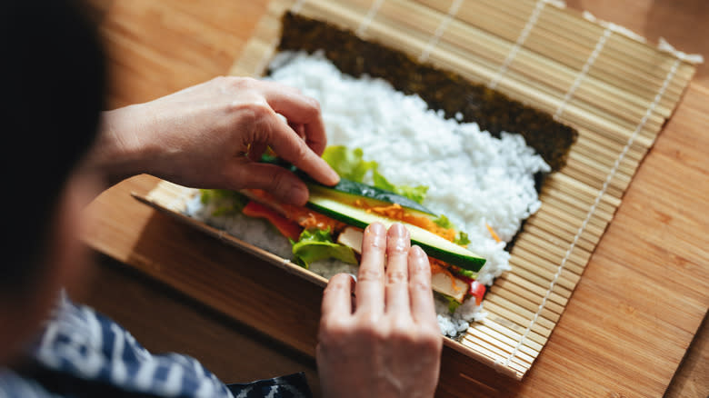 Person rolling fresh sushi roll 