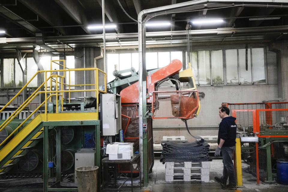 A worker checks an automatic machine composing the surface of the athletics track, at the Mondo factory, in Alba, northern Italy, Wednesday, March 13, 2024. The athletics track for the upcoming Paris Olympics is being produced by the Mondo company at its factory in northern Italy. The track is made in portions, rolled up and then will be transported to the Stade de France, where it will be installed over the next month. (AP Photo/Luca Bruno)