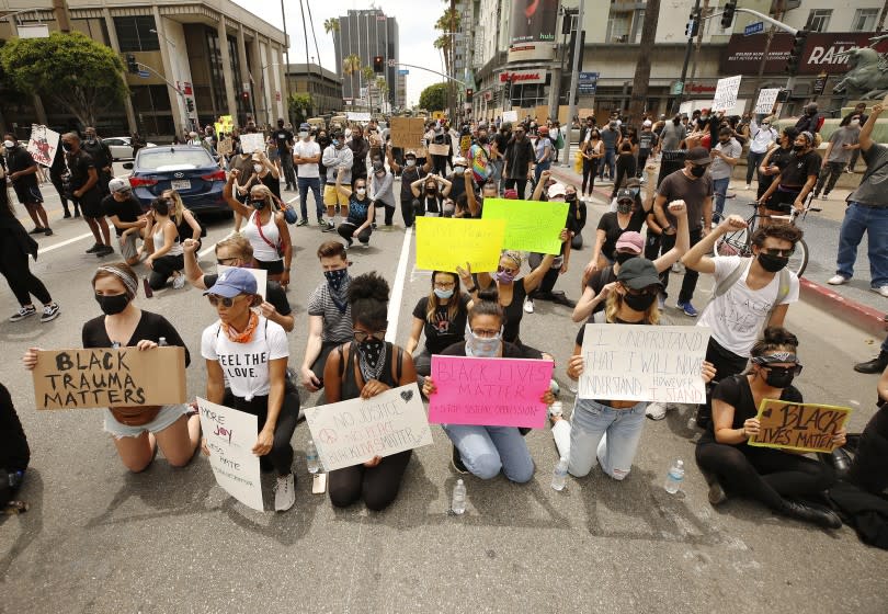 LOS ANGELES, CA - JUNE 02: Protestors take a knee in front of LAPD officers as they close Sunset Blvd at Vine Street in Hollywood while protesters made of mostly students marched through Hollywood Tuesday afternoon to protest the death of George Floyd during an arrest in Minneapolis last week. The group gathered at the intersection of Hollywood Blvd and Vine Street for a peaceful demonstration and marched through parts of Hollywood encountering LAPD officers and National Guardsmen. Hollywood on Tuesday, June 2, 2020 in Los Angeles, CA. (Al Seib / Los Angeles Times)