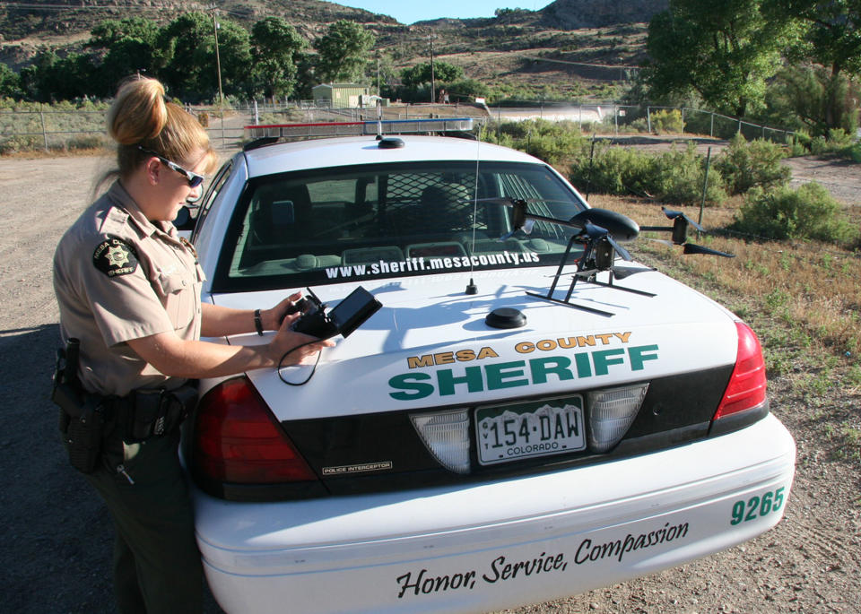 This undated photo provided by the Mesa County, Colo., Sheriff's Department, Deputy Amanda Hill of the Mesa County Sheriff’s Office in Colorado prepares to use a Draganflyer X6 drone equipped with a video camera to help search for a suspect in a knife attack in Mesa County, Colo. Civilian cousins of the unmanned military aircraft that have been tracking and killing terrorists in the Middle East and Asia are being sought by police departments, border patrols, power companies, news organizations and others who want a bird’s-eye view. (AP Photo/Mesa County Sheriff's Unmanned Operations Team)