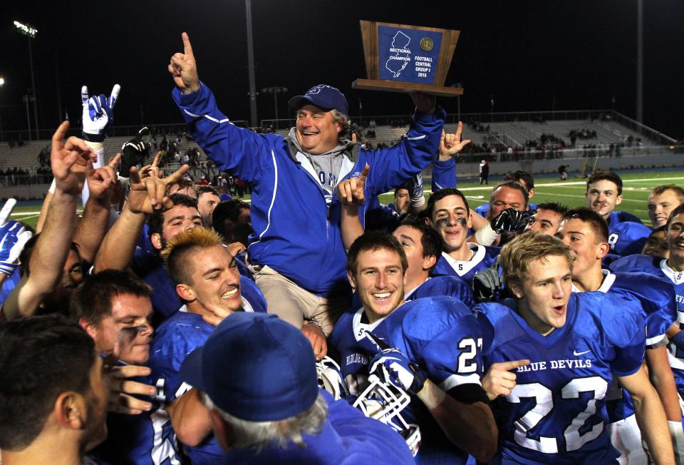 Shore Regional head coach Mark Constantino (center), in the blue jacket, is shown being hoisted by his players after the Blue Devils won the 2015 NJSIAA Central Group 1 championship and capped a 12-0 season with a 56-28 win over Palmyra.