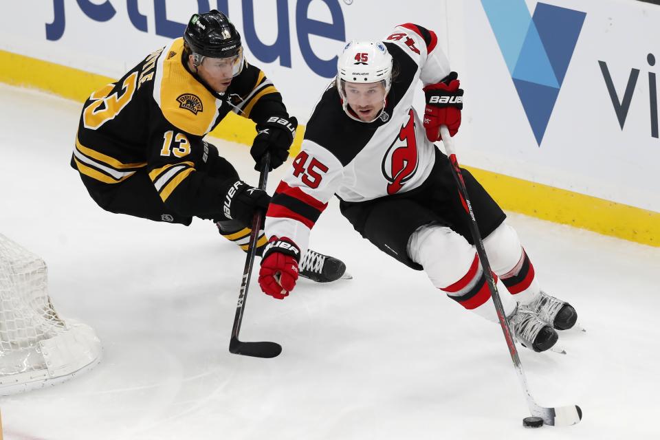 Boston Bruins' Charlie Coyle (13) battles New Jersey Devils' Sami Vatanen (45) for the puck during the first period of an NHL hockey game, Sunday, March 28, 2021, in Boston. (AP Photo/Michael Dwyer)