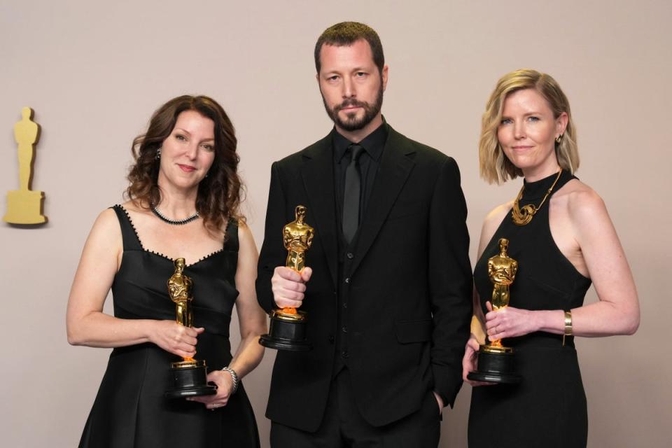 Raney Aronson-Rath, from left, Mstyslav Chernov, and Michelle Mizner pose in the press room with the award for best documentary feature film for 