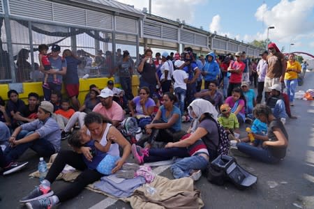 A group of migrants who returned to Mexico to await their U.S. asylum hearing block the Puerta Mexico international border crossing bridge