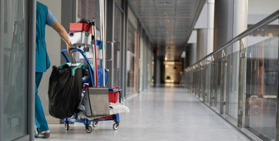 TUC An employee pulls a trolley for cleaning offices. Woman cleaner is engaged in work. Shopping center place for text