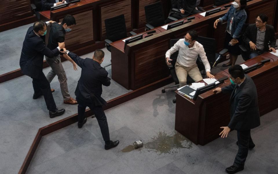Ted Hui (2-L) is restrained by security guards, after spilling a foul-smelling liquid during the third reading of the National Anthem bill at the Legislative Council in Hong Kong - JEROME FAVRE/EPA-EFE/Shutterstock /Shutterstock