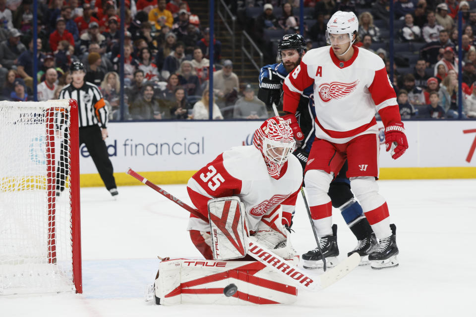 Detroit Red Wings' Ville Husso, left, makes a save as teammate Ben Chiarot, right, and Columbus Blue Jackets' Boone Jenner look for a rebound during the second period of an NHL hockey game on Sunday, Dec. 4, 2022, in Columbus, Ohio. (AP Photo/Jay LaPrete)