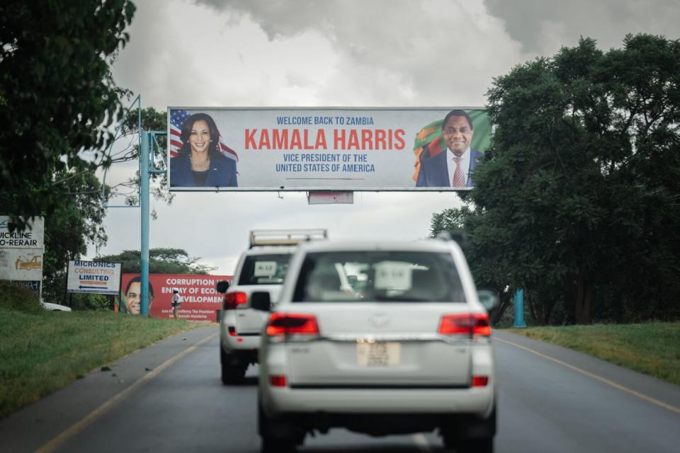 A sign welcoming Vice President Kamala Harris to Zambia hangs over the road as her motorcade passes through.
