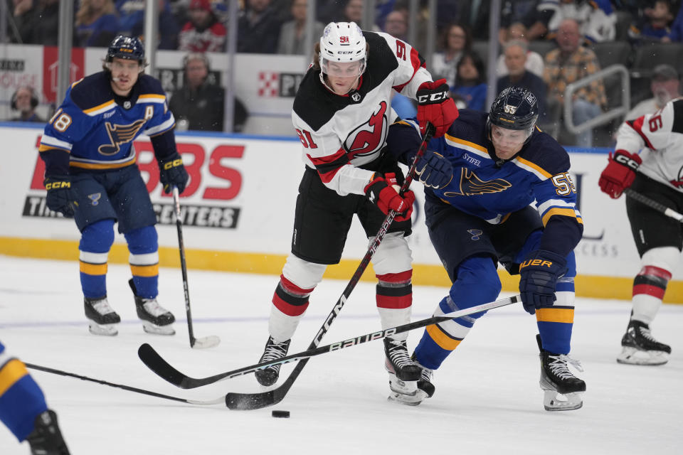 New Jersey Devils' Dawson Mercer (91) controls the puck as St. Louis Blues' Colton Parayko (55) defends during the first period of an NHL hockey game Friday, Nov. 3, 2023, in St. Louis. (AP Photo/Jeff Roberson)