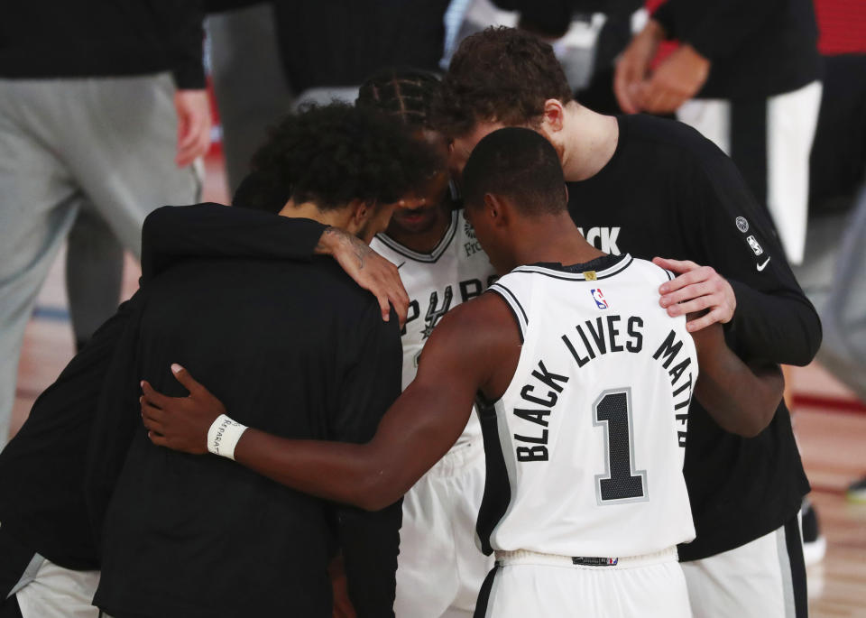 San Antonio Spurs guard Lonnie Walker IV (1) has Black Lives Matters on the back of his jersey in a huddle before an NBA basketball game against the Sacramento Kings, Friday, July 31, 2020, in Lake Buena Vista, Fla. (Kim Klement/Pool Photo via AP)