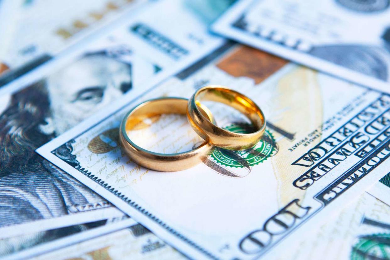 <p>Getty</p> A stock image of wedding rings and money