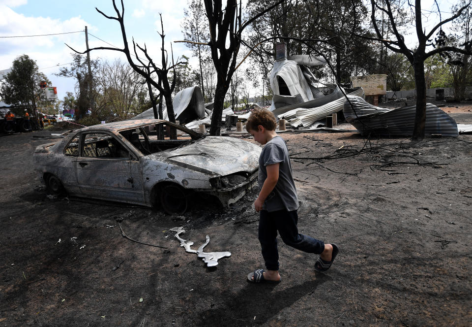 Eight year-old Jarrod McInnes walks next to the remains of a house that his family was about to buy and was destroyed by bushfires in Rappville. Source: AAP Image/Dan Peled.