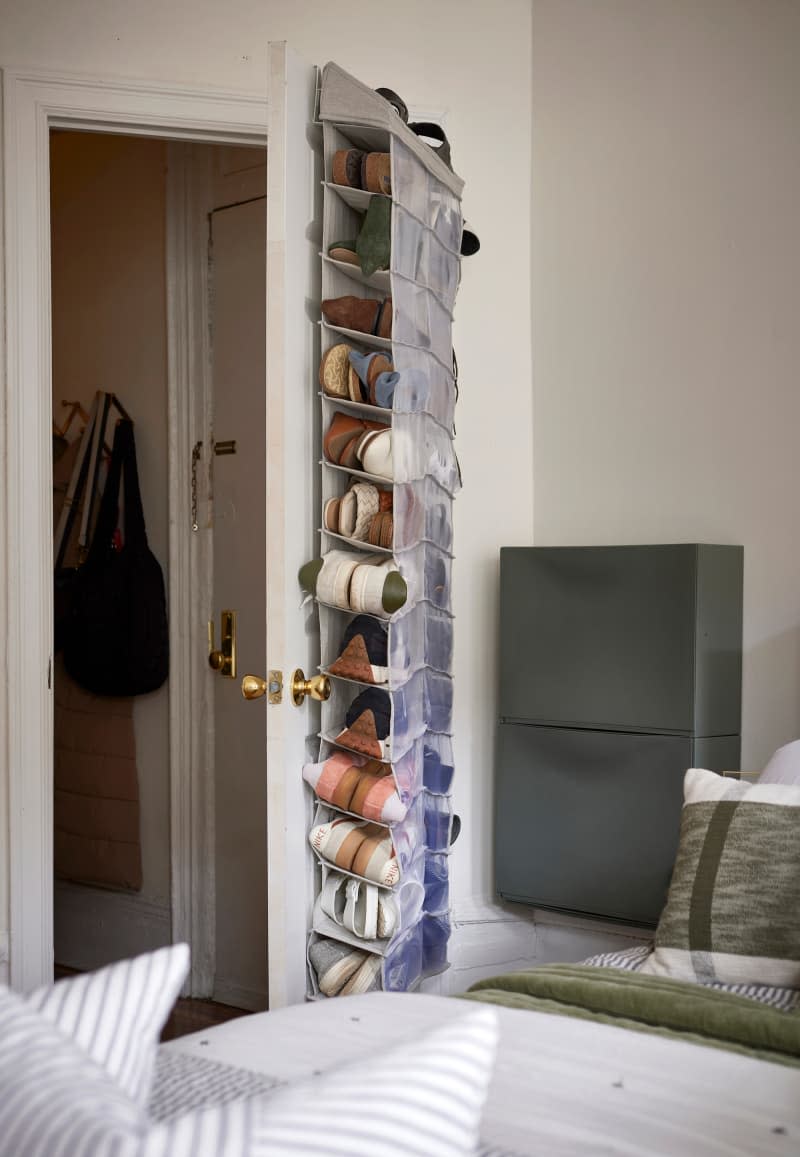 Shoes hang on door in neutral bedroom.