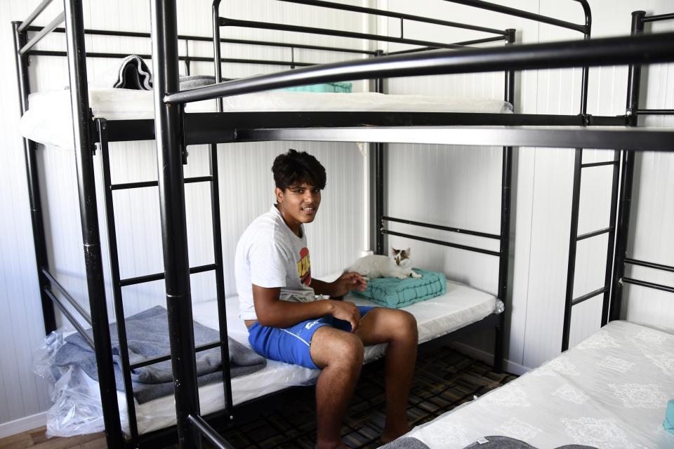 A migrant with his cat arrives at a container house at the new closed monitored facility in Zervou village, on the eastern Aegean island of Samos, Greece, Monday, Sept. 20, 2021. The transfer of the migrants to the new, €43 million ($50 million) facility began Monday and be completed by Wednesday. (AP Photo/Michael Svarnias)