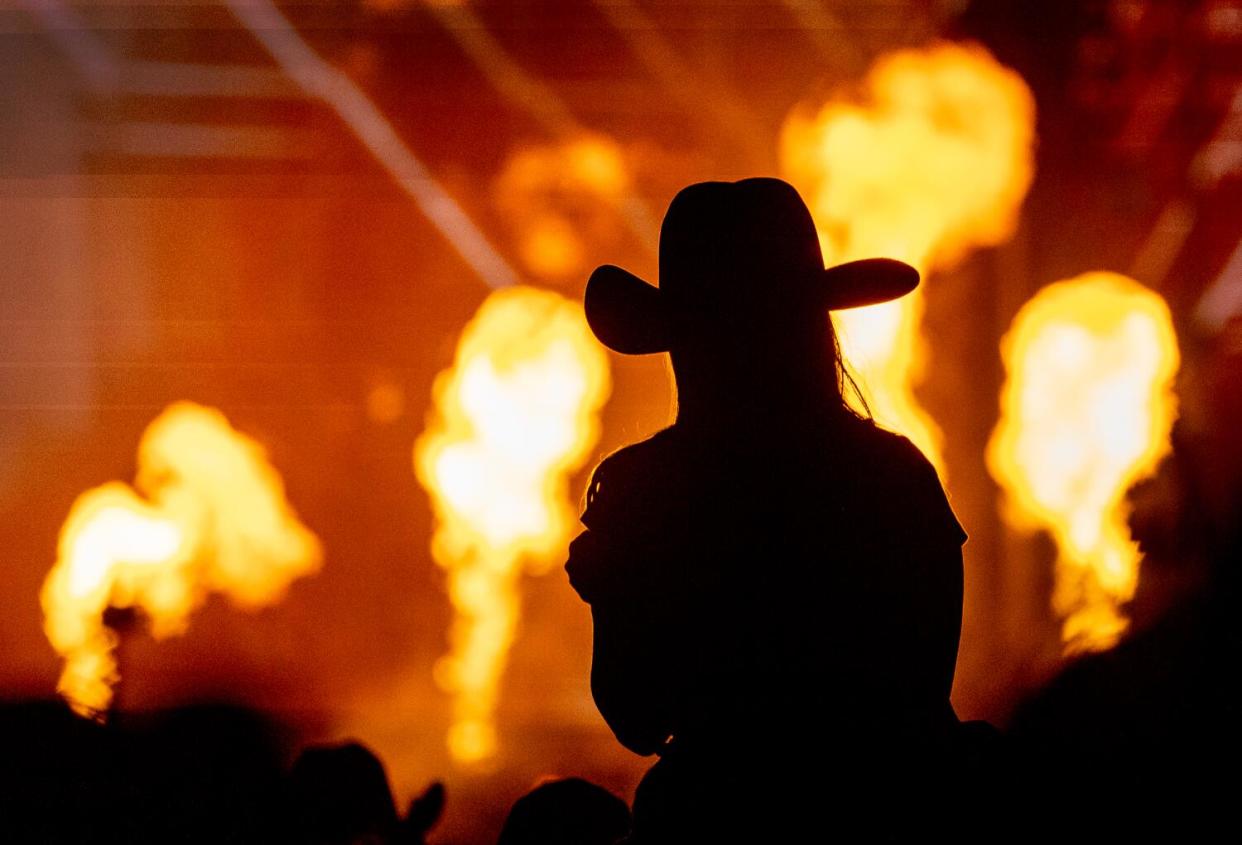 Silhouette of a woman wearing a cowboy hat against a pyrotechnic display