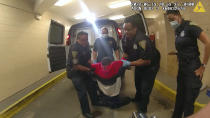 In this frame taken from police body camera video, Richard Cox, center, is placed in a wheel chair after being pulled from the back of a police van after being detained by New Haven Police, June 19, 2022, in New Haven, Conn. Officials in Connecticut said, Wednesday, June 22, 2022, that two New Haven officers have been placed on paid leave and three others were reassigned after Cox was seriously injured in the back of a police van. (New Haven Police via AP)