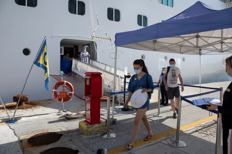 Passengers wearing protective face mask disembark from the Costa Luminosa cruise ship at the port of the island of Corfu