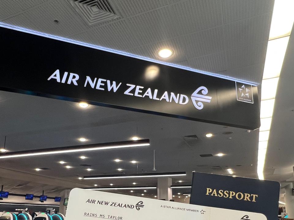 Holding my boarding pass and passport in front of the ANZ sign.