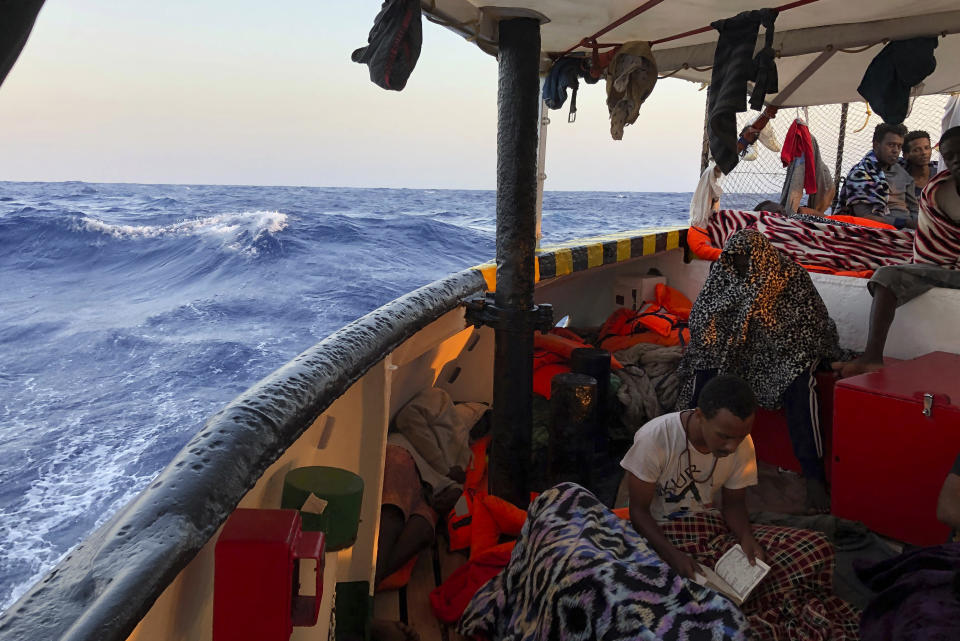 A migrant reads verses of the Quran aboard the Open Arms Spanish humanitarian boat as it arrives near Lampedusa coast in the Mediterranean Sea, Thursday, Aug.15, 2019. A Spanish aid boat with 147 rescued migrants aboard is anchored off a southern Italian island as Italy's ministers spar over their fate. (AP Photo/Francisco Gentico)