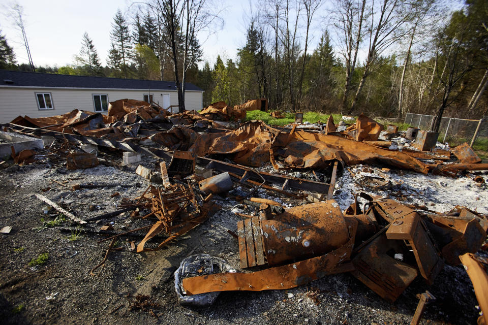 The remains of a home that burned down during the Echo Mountain fire are seen in Otis, Ore., on Thursday, May. 13, 2020. The small Oregon coast town is still recovering from the devastating fire that destroyed 293 homes. Experts say the 2020 wildfire season in Oregon was a taste of what lies ahead as climate change makes blazes more likely and more destructive even in wetter, cooler climates like the Pacific Northwest. (AP Photo/Craig Mitchelldyer)