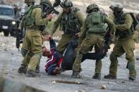 Israeli soldiers detain a wounded Palestinian stone thrower during clashes in Beit El, on the outskirts of the West Bank city of Ramallah, on October 7, 2015