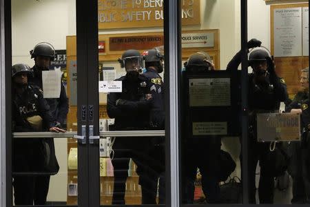 Members of the Berkeley Police Department look out of the police headquarters as protesters march against the New York City grand jury decision to not indict in the death of Eric Garner in Berkeley, California December 8, 2014. REUTERS/Stephen Lam