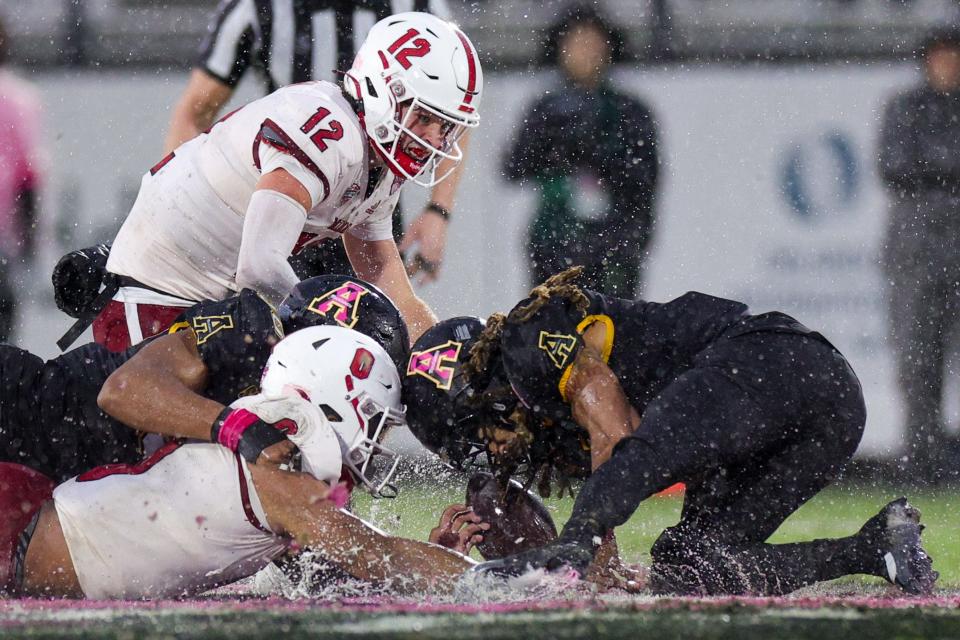Dec 16, 2023; Orlando, FL, USA; Miami (OH) Redhawks running back Rashad Amos (0) and Appalachian State Mountaineers safety Nick Ross (4) scramble for a loose ball in the second quarter during the Avocados from Mexico Cure Bowl at FBC Mortgage Stadium.