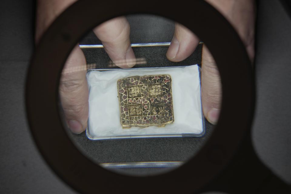 Liz Barham, senior conservator of the Museum of London Archaeology, displays an early medieval gold and gemstone necklace during a photo call, in London, Tuesday, Dec. 6, 2022. Archaeologists say a 1,300-year-old gold and gemstone necklace found during construction of a housing development marks the grave of a powerful woman who may have been an Anglo-Saxon aristocrat or early Christian religious leader in Britain. (AP Photo/Kin Cheung)