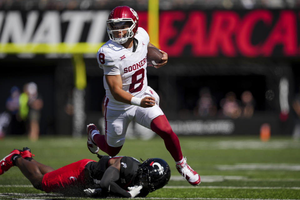 Oklahoma quarterback Dillon Gabriel (8) runs with the ball as he avoids Cincinnati safety Bryon Threats (10) during the first half of an NCAA college football game, Saturday, Sept. 16, 2023, in Cincinnati. (AP Photo/Aaron Doster)