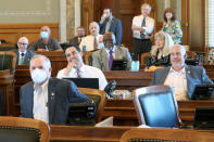 In this Thursday, June 4, 2020, photo, Republican members of the Kansas House, some wearing protective masks and some not, listen to humorous announcements as they prepare to take a lunch break, at the Statehouse in Topeka, Kan. During a two-day special session of the Legislature most Republican lawmakers did not wear masks, while most Democrats did. The issue is one of many creating a partisan divide in state legislatures across the U.S. (AP Photo/John Hanna)