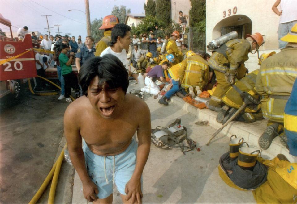 A young man weeps after seeing a dead child in front of an apartment in the Westlake district that was devastated by fire.