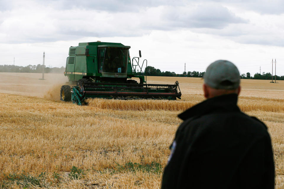 A farmer looks on as a combine harvests barley grains in a field in the Odesa region of Ukraine, June 23, 2022. (Photo by Pavlo Gonchar/SOPA Images/LightRocket via Getty Images)